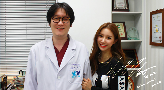 ジュエリー美容外科の院長と一緒に正面を眺めながら笑っている韓国のタレント、キム·ソウンさん。 さらに写真右下にキム·ソウンさんのサインもあります。